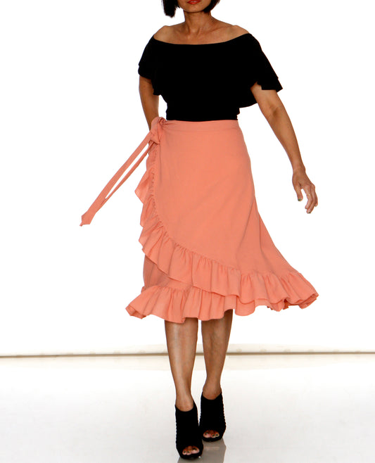 Woman wearing peach ruffled free size wrap skirt with a black top on a white background WA000197